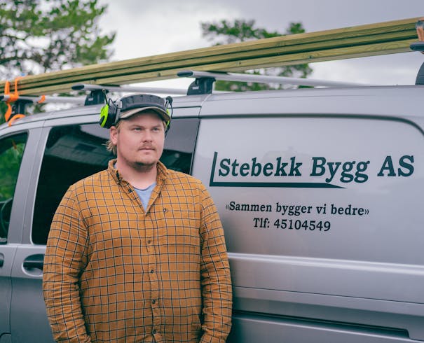 Tømrer Fredrik Stebekk foran firmabilen til Stabekk Bygg AS