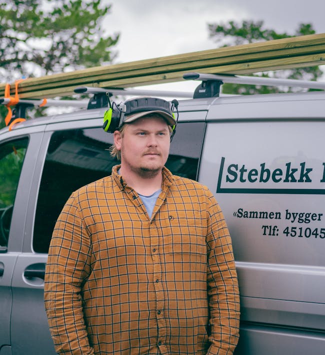 Tømrer Fredrik Stebekk foran firmabilen til Stabekk Bygg AS