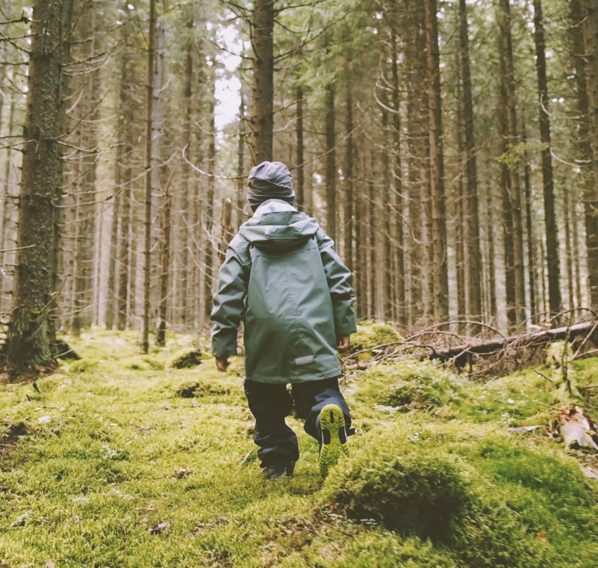 Lapset sadevaatteissa juoksevat metsässä