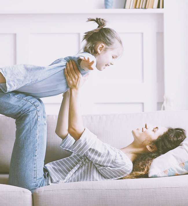 Äiti makaa sohvalla ja nostaa tyttären ylös